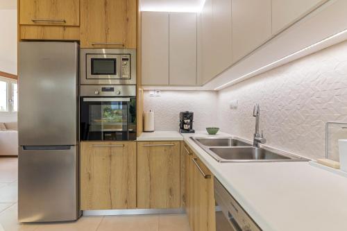 Una cocina con electrodomésticos de acero inoxidable y gabinetes de madera. en Villa Carpe Diem - 2BR - 300m to Beach, en Heraklion