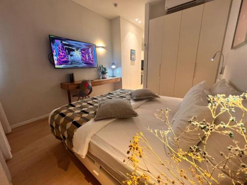 Dizengoff 208 Hotel Tel Aviv في تل أبيب: غرفة نوم مع سرير وتلفزيون على الحائط
