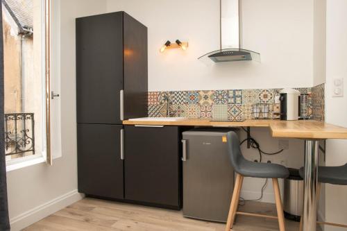 uma cozinha com um frigorífico preto e uma mesa em Grand studio industriel dans le centre historique em Poitiers
