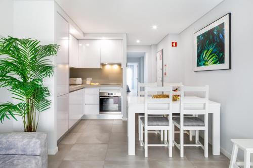 a white kitchen with a white table and chairs at Kasino II 1º A in Monte Gordo