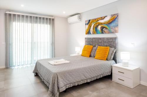 ein Schlafzimmer mit einem Bett mit gelben Kissen und einem Gemälde in der Unterkunft Kasino II 1º A in Monte Gordo