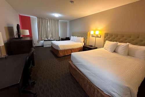 una camera d'albergo con due letti e una televisione di Ramada by Wyndham Estevan a Estevan