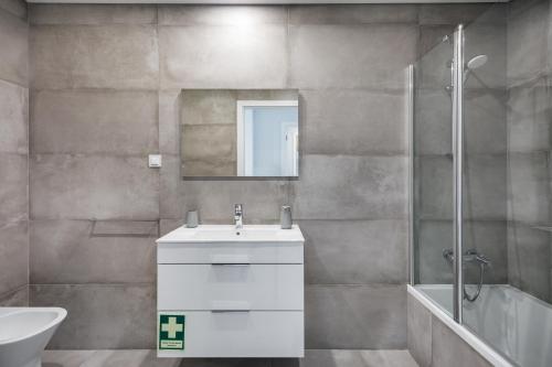 ein Badezimmer mit Waschbecken, Dusche und Spiegel in der Unterkunft Kasino II 1º A in Monte Gordo