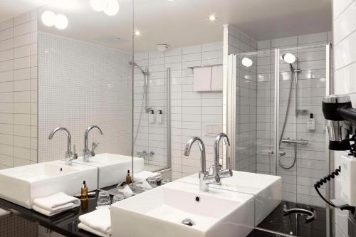 uma casa de banho com 2 lavatórios e um chuveiro em Scandic Victoria Tower em Estocolmo