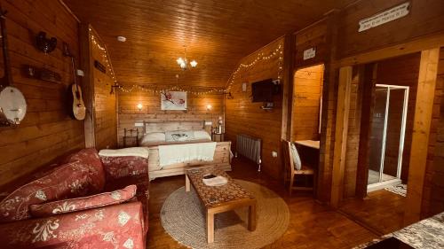 a room with a couch and a bed in a cabin at Blossom Cabin - Little log Cabin in Wales in Newtown