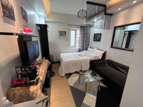 マニラにあるMe N’ My Bed Staycation @ SMDC Trees Residencesのベッド2台、ソファ、テレビが備わる客室です。