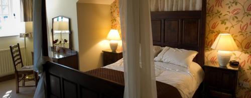 een slaapkamer met een bed, 2 lampen en een spiegel bij True Lovers Knot in Blandford Forum