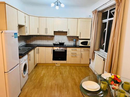 kuchnia z białymi szafkami i szklanym stołem w obiekcie One Bedroom Flat/Apartment. w mieście Bexleyheath