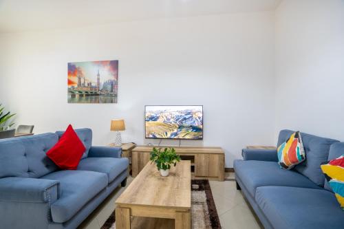 Sala de estar con sofás azules y mesa de centro en RH- Experience Comfort and Convenience in our 2BR, Al Barsha en Dubái