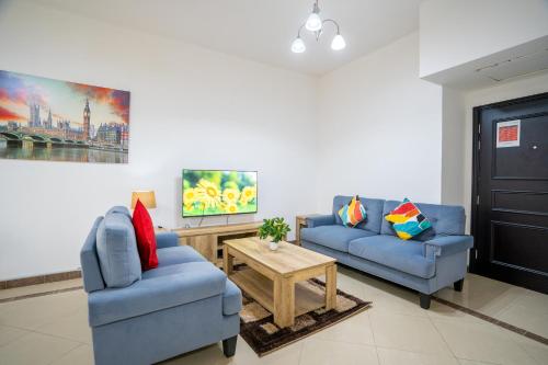 uma sala de estar com dois sofás azuis e uma mesa em RH- Experience Comfort and Convenience in our 2BR, Al Barsha em Dubai