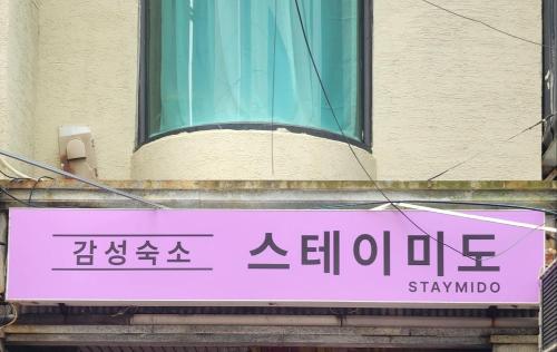 ein rosa Schild an der Seite eines Gebäudes in der Unterkunft Stay Mido in Busan