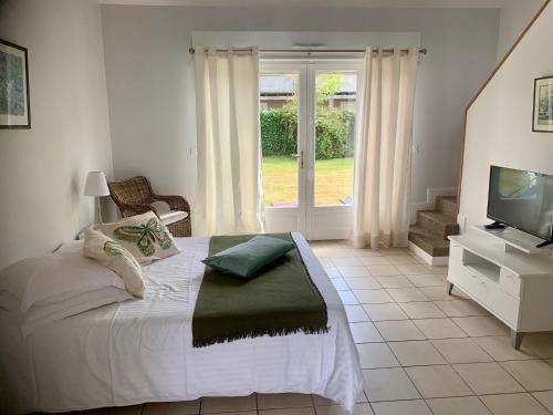 a bedroom with a bed and a tv and a window at La Sapinière in Saint-Laurent-sur-Mer