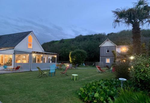 a house with a yard with chairs and a tree at La Sapinière in Saint-Laurent-sur-Mer