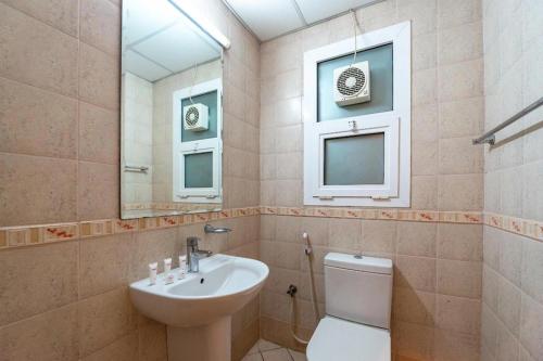 y baño con lavabo, aseo y espejo. en Zenith Smart Vacation Homes, Sharjah, en Sharjah