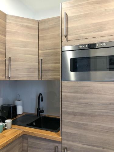 La cuisine est équipée de placards en bois et d'un four micro-ondes en acier inoxydable. dans l'établissement LÉchappée Belle Métro 9 WiFi-Clim-NETFLIX, à Montreuil