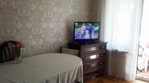 a room with a television on a dresser with a table at 2-ух комнатная квартира in Baku