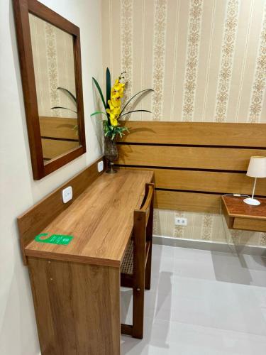 a wooden desk with a vase of flowers on it at Dublin Hotel in São Paulo