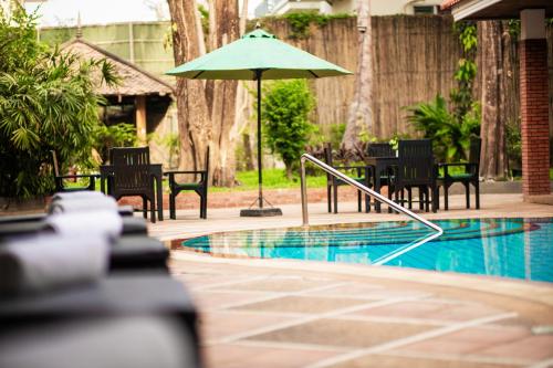 um pátio com cadeiras e um guarda-sol ao lado de uma piscina em ANGKOR TRAILS Residence em Siem Reap
