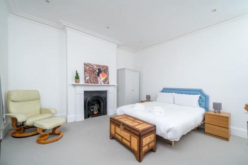 a bedroom with a bed and a chair and a fireplace at Stunning house near Notting Hill in London