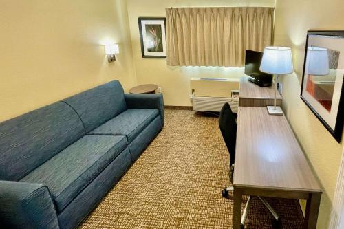 a living room with a blue couch in a hotel room at Suburban Studios Fort Myers Cape Coral in Fort Myers