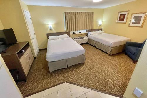 a hotel room with two beds and a television at Suburban Studios Fort Myers Cape Coral in Fort Myers