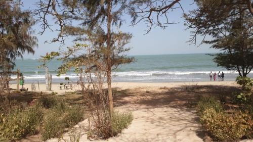 a beach with people walking on the sand and the ocean at Simple Life on Baobab Beach in Tanji