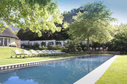 a swimming pool with lounge chairs in a yard at Constantia Klein in Cape Town