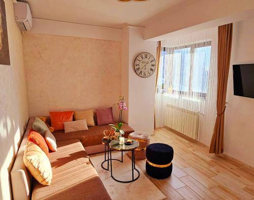 uma sala de estar com um sofá e um relógio na parede em Iaki Apartment Mamaia em Mamaia