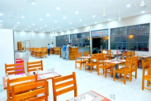 een restaurant met houten tafels en stoelen en mensen erin bij Hotel Mint Leaf in Kāgal