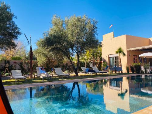 una piscina con sillas y árboles y un edificio en villa roswell marrakech, en Marrakech