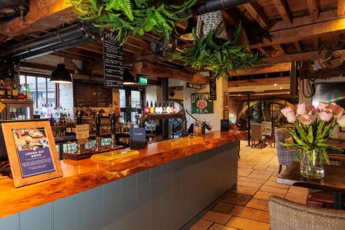 a bar in a restaurant with flowers on the counter at Egypt Mill Hotel and Restaurant in Nailsworth