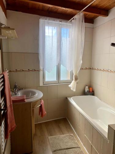 une salle de bain avec une baignoire, un lavabo et une fenêtre dans l'établissement Maison de village aux portes de Toulouse, à Fenouillet