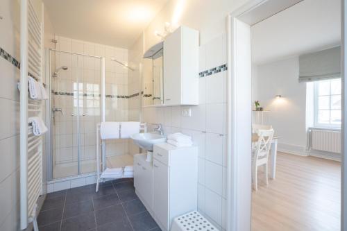 La salle de bains blanche est pourvue d'un lavabo et d'une douche. dans l'établissement Gut Oehe, à Maasholm