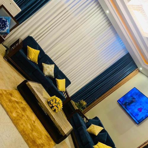 ein Wohnzimmer mit einem blauen Sofa und gelben Kissen in der Unterkunft ZEMARIAS INTERNATIONAL HOTEL in Mekʼelē