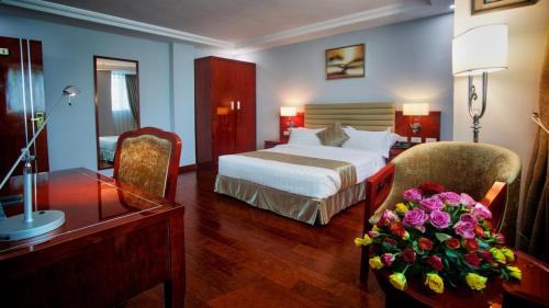 Habitación de hotel con cama, escritorio y mesa con flores en ZEMARIAS INTERNATIONAL HOTEL en Mekʼelē