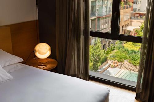 a bedroom with a bed and a large window at Alexandra Barcelona Hotel, Curio Collection by Hilton in Barcelona