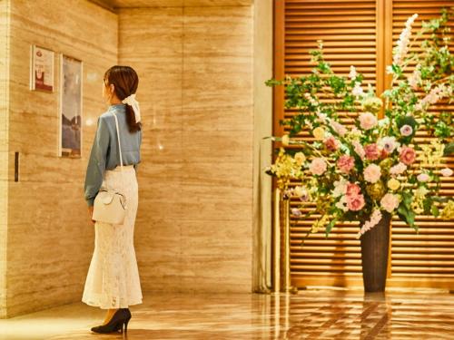 a woman standing next to a vase of flowers at Kansai Airport Washington Hotel in Izumi-Sano