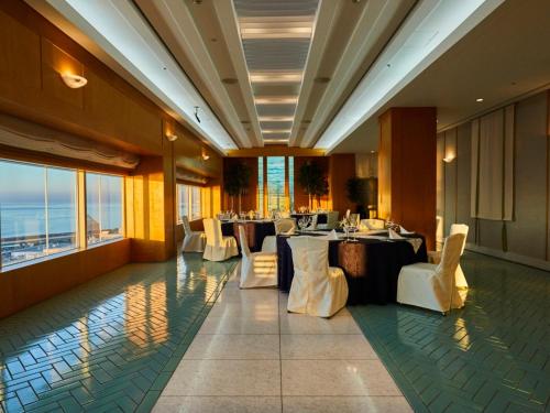 a restaurant with tables and white chairs and windows at Kansai Airport Washington Hotel in Izumi-Sano
