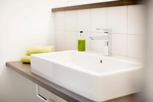 a white bathroom sink with a green bottle on it at Boardinghouse by M&K in Bad Oeynhausen