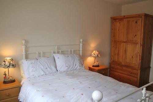um quarto com uma grande cama branca e 2 candeeiros em Claddaghduff 302 Gannoughs em Claddaghduff