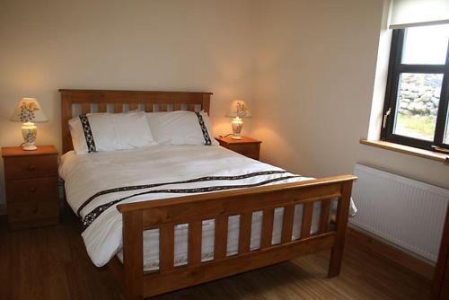 um quarto com uma cama de madeira e 2 candeeiros nas mesas em Claddaghduff 302 Gannoughs em Claddaghduff