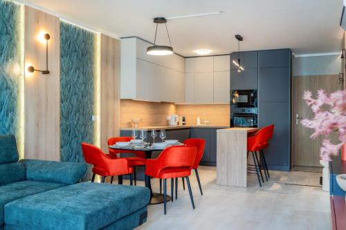 a living room and kitchen with a table and red chairs at MyFlat Wave Botanic Apartment in Siófok