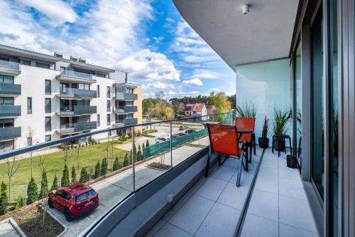 a balcony with a red chair and a view of a car at MyFlat Wave Botanic Apartment in Siófok