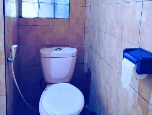 a bathroom with a white toilet in a tiled wall at MamaRoos Reborn Home Stay in Rinondoran