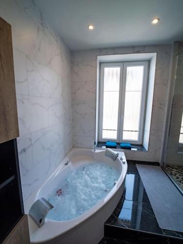a large bath tub in a bathroom with a window at Duplex Jeanne d'Arc Billard Baby en option Escape Game Logements Insolites in Nancy