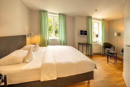 1 dormitorio con 1 cama blanca grande con cortinas verdes en Der Charlottenhof en Ahrenshoop