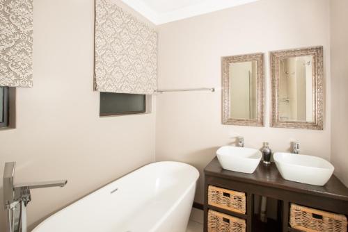a bathroom with a tub and a sink and mirror at Guesthouse Fort Knox in Kokstad