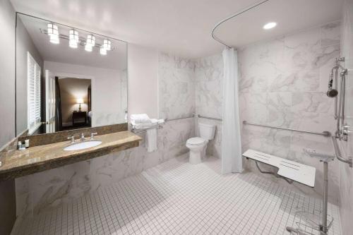 a white bathroom with a sink and a toilet at The Lafayette by LuxUrban in New Orleans