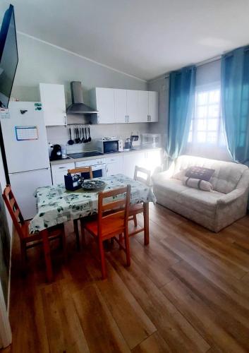 eine Küche und ein Wohnzimmer mit einem Tisch und einer Couch in der Unterkunft casa las olas in Costa Del Silencio