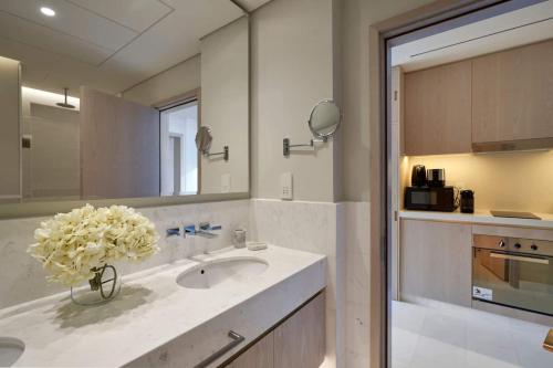 ein Badezimmer mit einem Waschbecken und einer Vase aus Blumen in der Unterkunft Extravagant Palm Studio In 5-star Hoteloceanview in Dubai